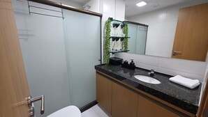 A modern bathroom with a glass shower enclosure, a sink with a black countertop, and a mirror above the sink.