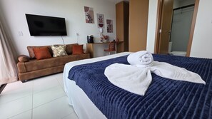 Una camera d'albergo con un letto, un divano, una televisione e una scrivania.