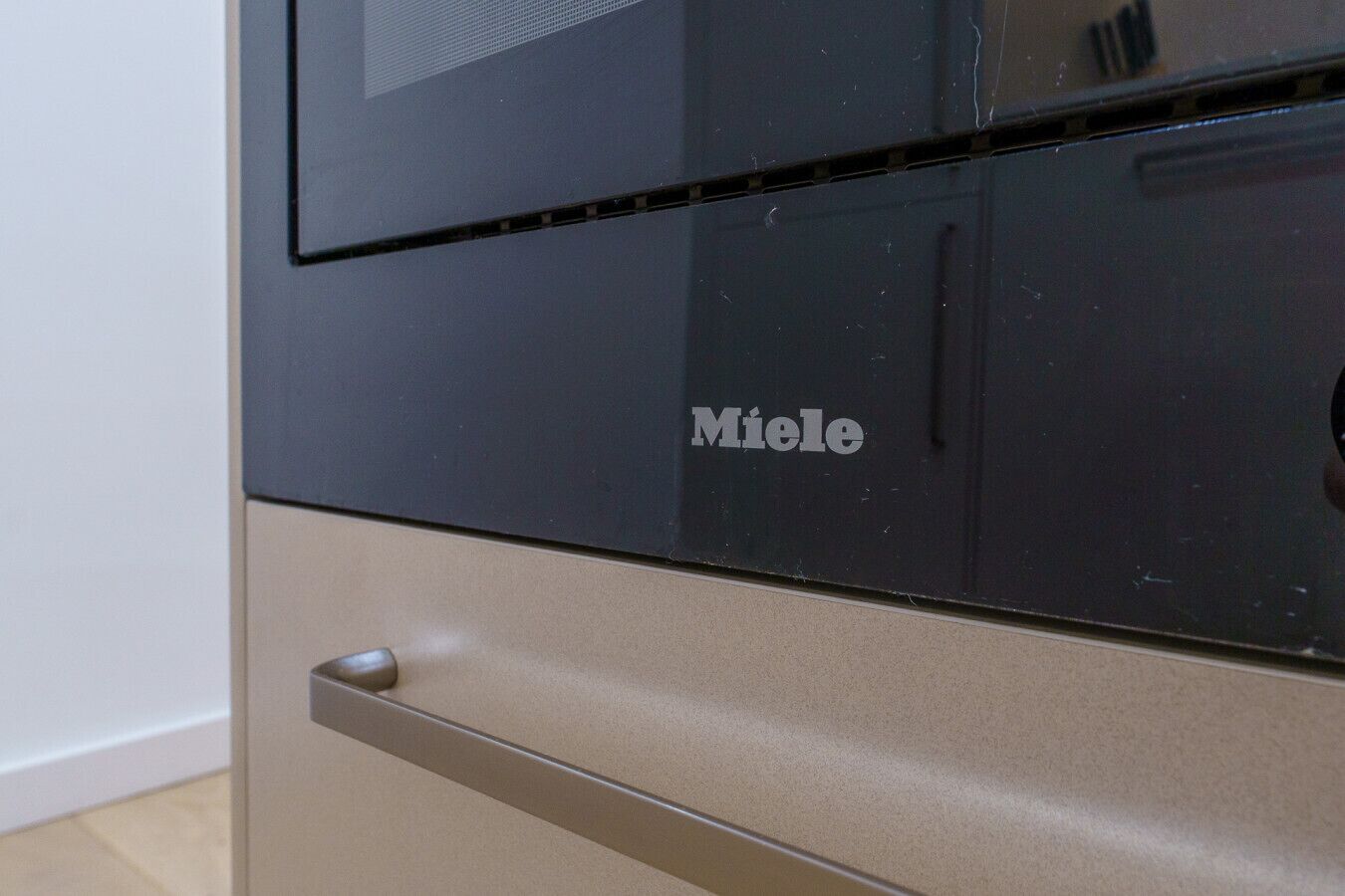 A kitchen with a black microwave and a beige oven.