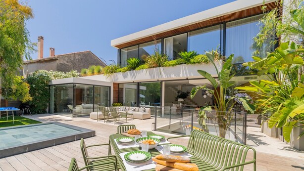 A modern outdoor dining area with a pool, green furniture, and lush plants. - Villa Roche Blanche - Jardin tropical avec piscine (Marseille)