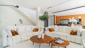 A modern living room with a white sofa, a coffee table, and a staircase. - Villa Roche Blanche - Jardin tropical avec piscine (Marseille)
