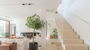 A modern living room with a large potted tree, a staircase, and a dining area. - Villa Roche Blanche - Jardin tropical avec piscine (Marseille)