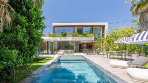 A modern house with a swimming pool, outdoor furniture, and lush greenery. - Villa Roche Blanche - Jardin tropical avec piscine (Marseille)