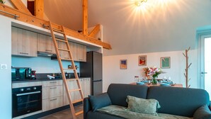A modern kitchen with wooden beams, a built-in oven, and a ladder.
