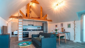 A modern living space with a kitchen, dining area, and a loft bedroom.