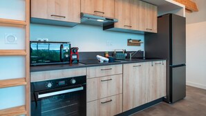 A modern kitchen with wooden cabinets, a stainless steel refrigerator, a built-in oven, and a microwave.