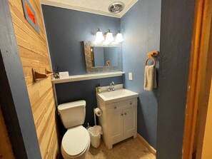 Een badkamer met toilet, wastafel en spiegel.