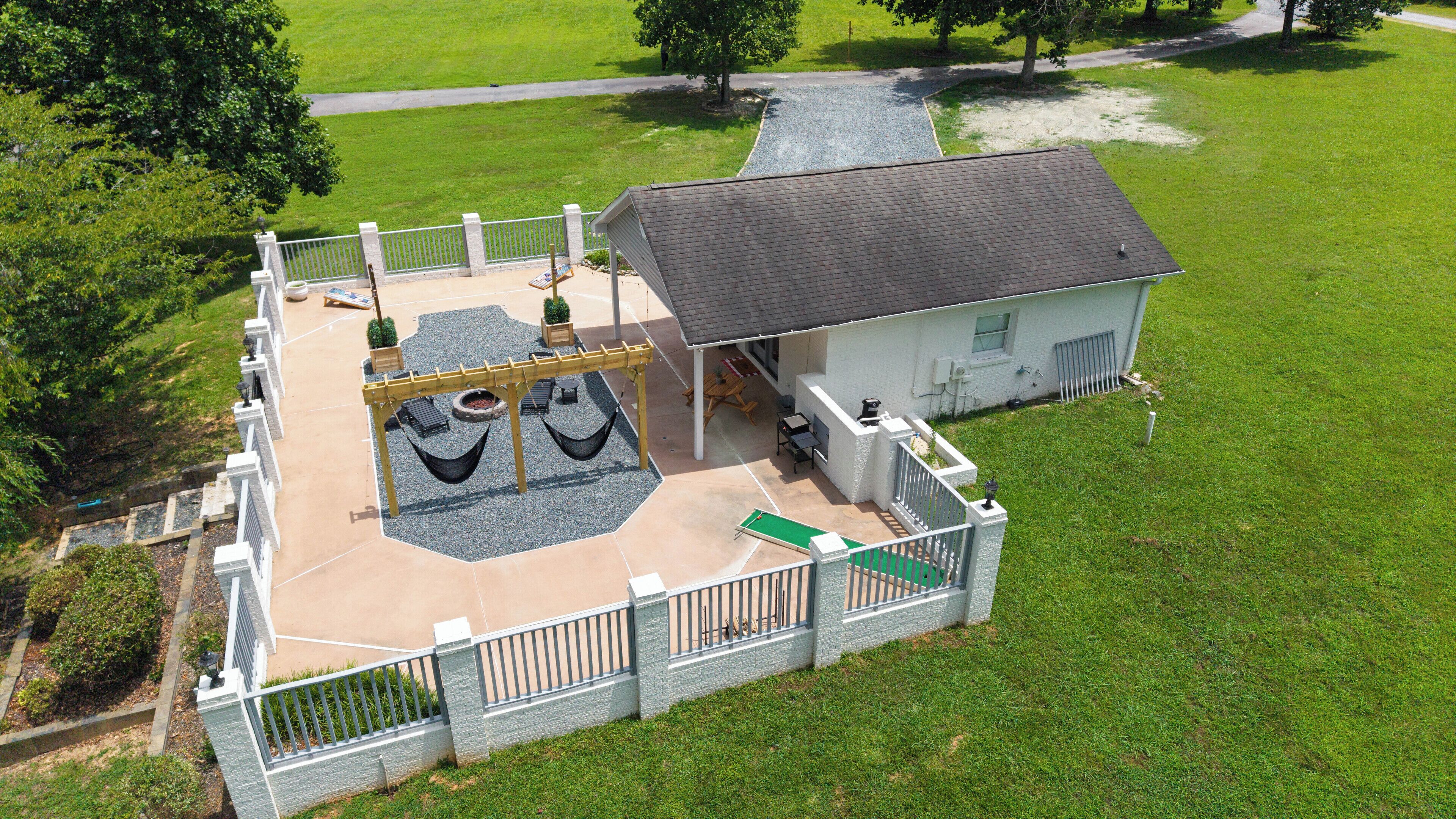 An aerial view of a property with a fenced patio area, outdoor seating, and a small building.