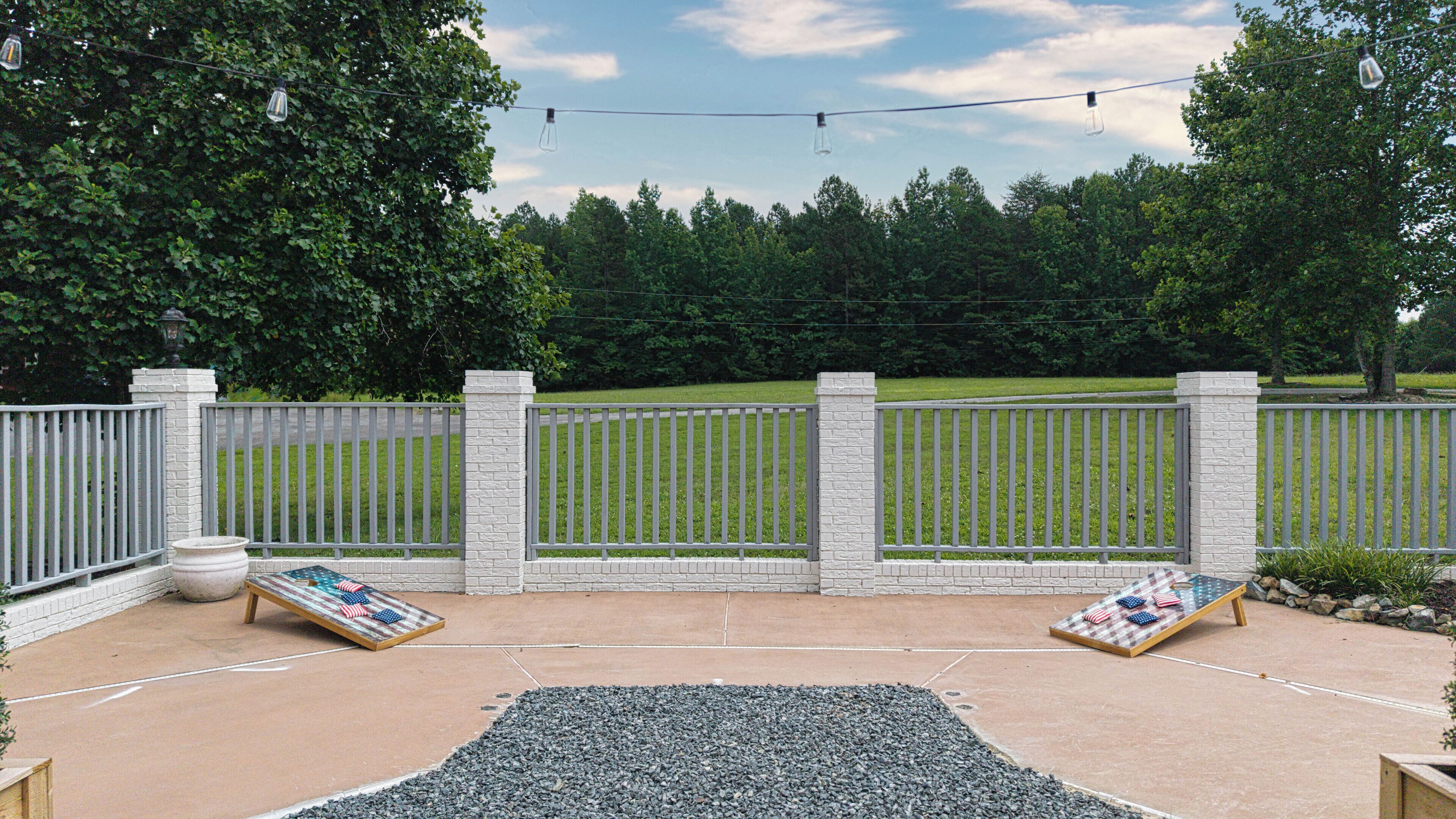 A patio area with a concrete floor, two Adirondack chairs, a small table, and a decorative rug.