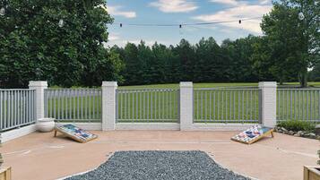 A patio area with a concrete floor, two Adirondack chairs, a small table, and a decorative rug.