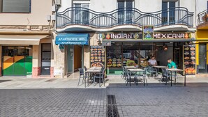 A restaurant with outdoor seating, a balcony, and a sign for 'Indian Menu.'