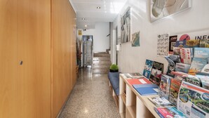 A hallway with wooden lockers, a staircase, and a wall with various magazines and books.
