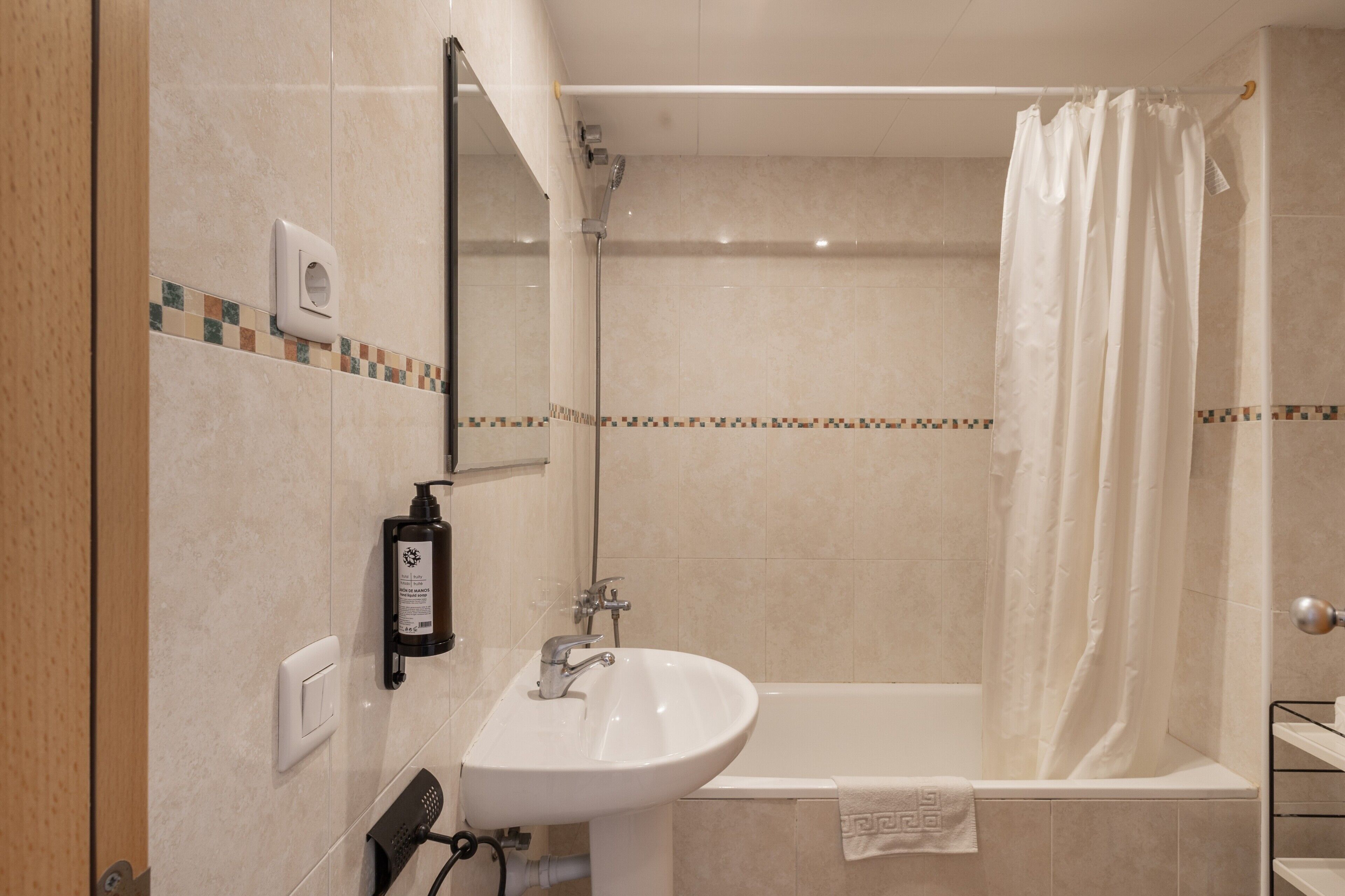 Un baño con lavamanos, espejo, cortina de ducha y una toalla en la bañera.
