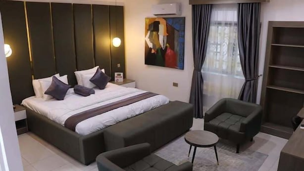 Een moderne hotelkamer met een groot bed, een bank, een klein tafeltje en een boekenkast.