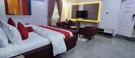 A modern hotel room with a large bed, a desk, a TV, and a wardrobe.