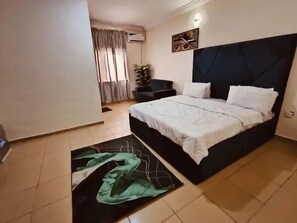 Een slaapkamer met een bed, een stoel, een kamerplant en een schilderij aan de muur.