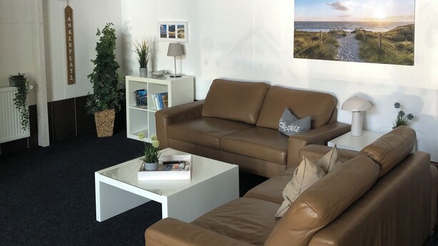 A modern living room with a high ceiling, a loft area, and a large window with a scenic view.