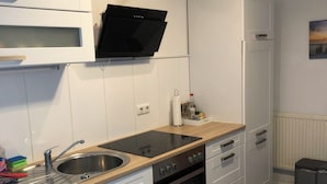 A modern kitchen with white cabinetry, a black stove, a built-in microwave, and a stainless steel sink.
