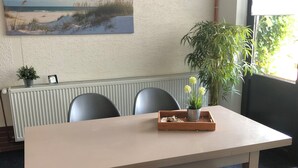 A conference room with a long table, four chairs, a potted plant, and a painting on the wall.