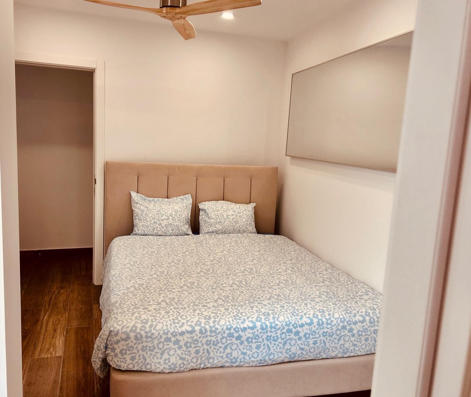 A bedroom with a bed, a ceiling fan, and a door.