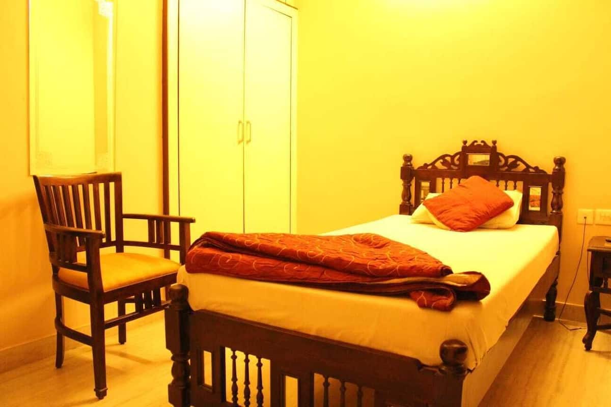 A bedroom with a wooden bed, a chair, and a wardrobe.