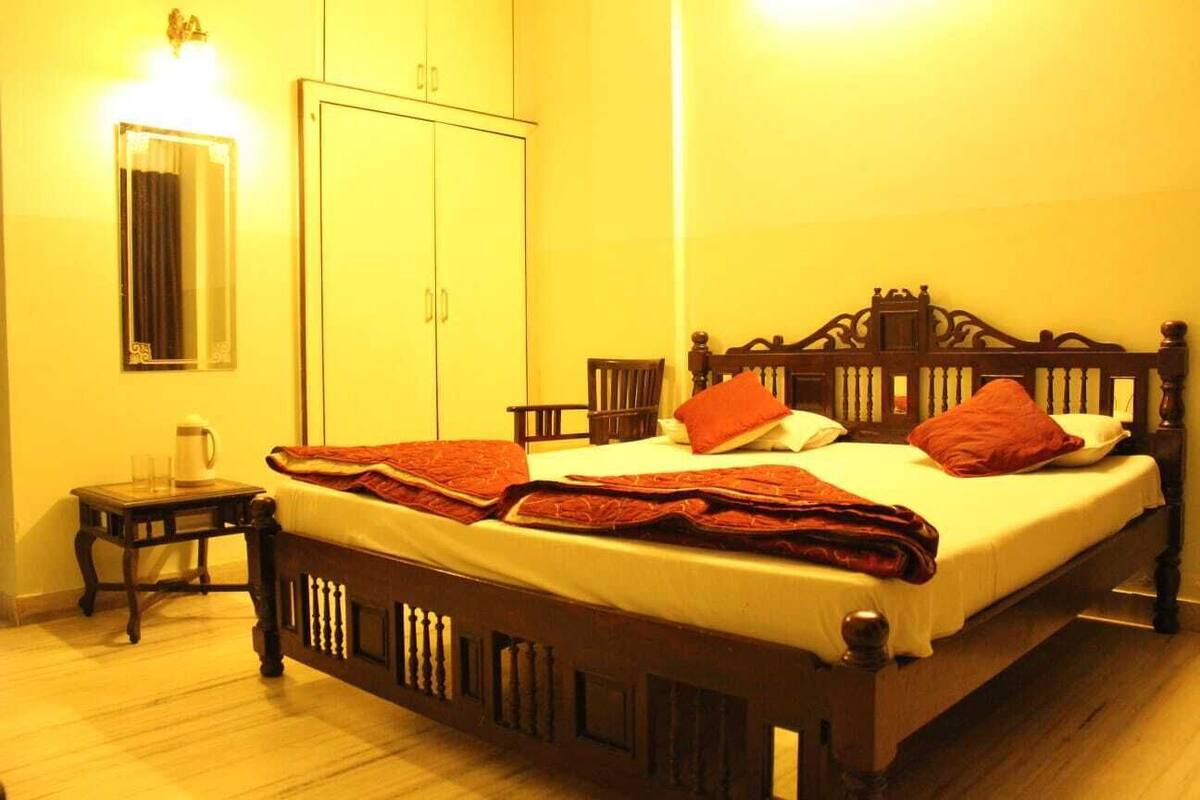 A bedroom with a wooden bed, a nightstand, a wardrobe, and a mirror.