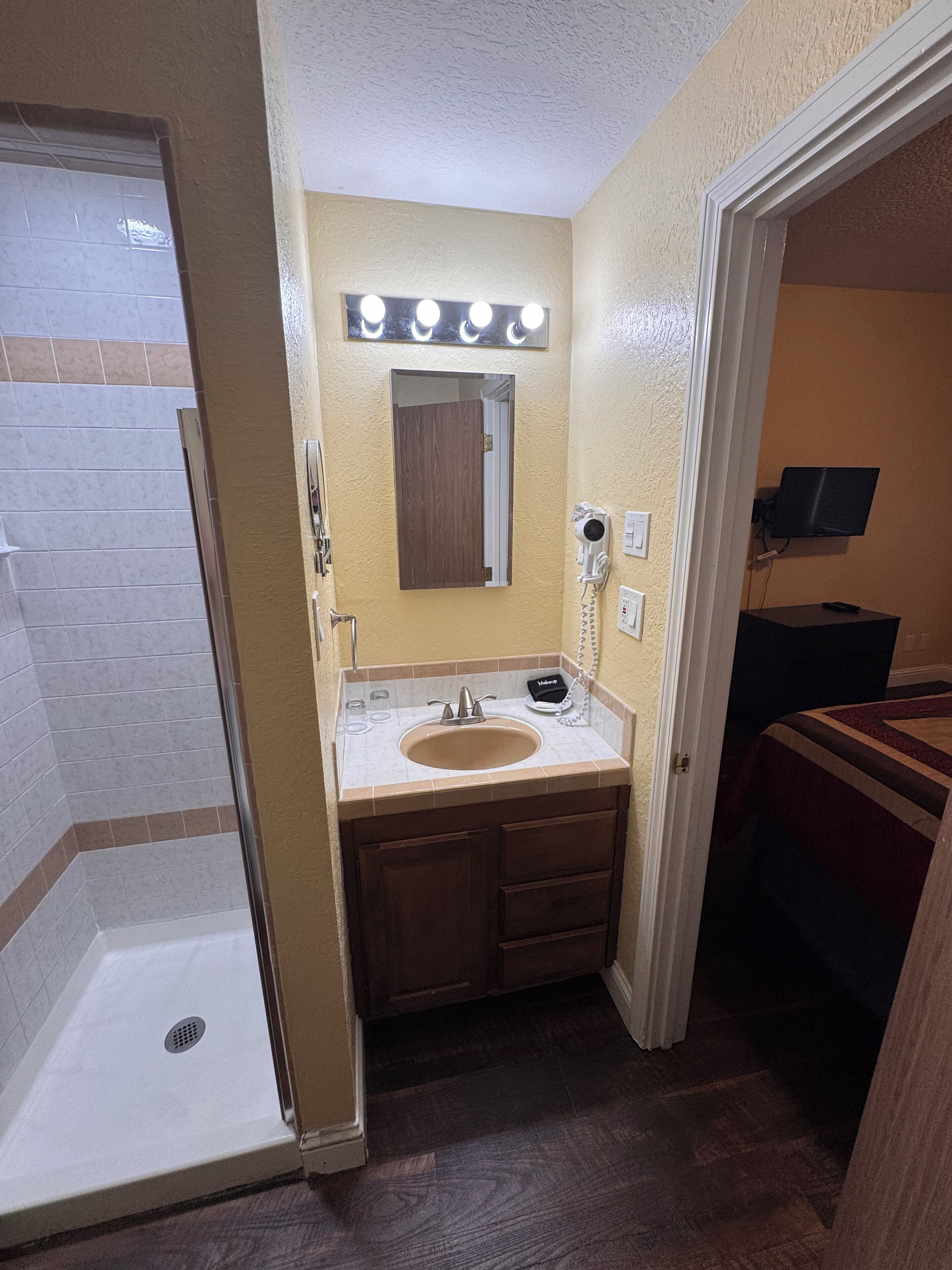 Une salle de bain comprenant une douche, un lavabo avec un meuble-vasque, un miroir avec éclairage et des toilettes.
