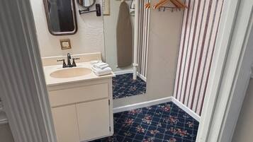 A bathroom with a sink, mirror, and a shower area.