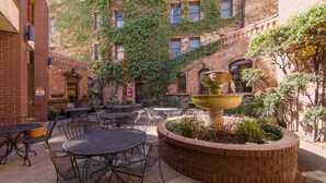 An outdoor patio area with brick walls, a fountain, and multiple tables and chairs.