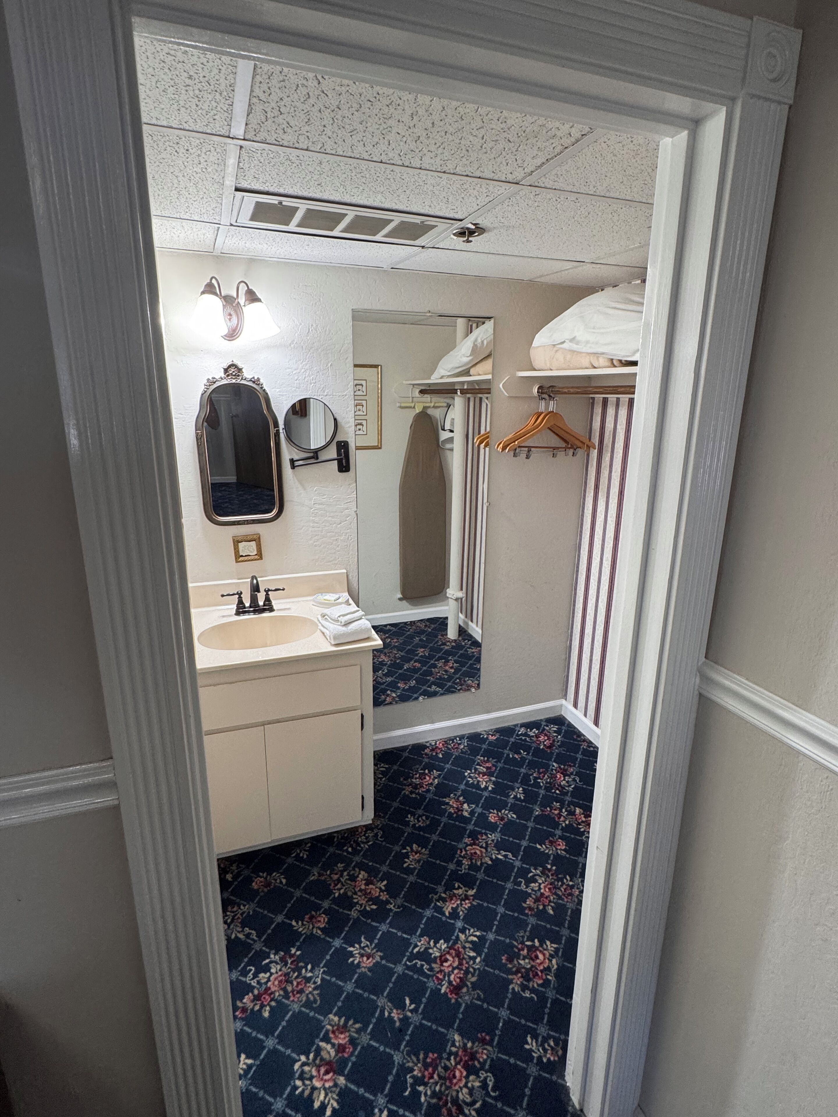 A bathroom with a sink, mirror, and towel rack.