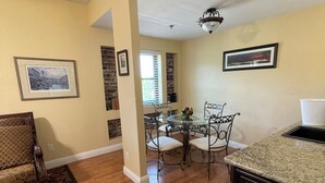 A spacious dining area with a glass table and chairs, a kitchen with dark cabinetry, and a patterned rug on the floor. - Boutique Retreat in Wine & Gold Country (Placerville)