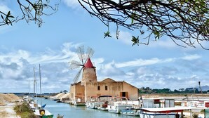 A coastal scene with a windmill, boats, and a café with blue chairs. - Holiday Home 'La Piazzetta' with Wi-Fi and Air Conditioning (Marsala)