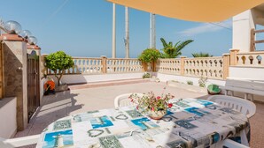 A terrace with a table set for dining, a potted plant, and a view of the sea. - Holiday Home 'Casa Damari-Beachfront' with Sea View and Private Terrace (Petrosino)