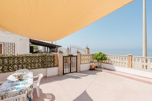 Eine Terrasse mit Esstisch, einem Tor und Blick auf das Meer.