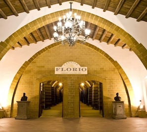 An arched library interior with a chandelier, bookshelves, and busts.