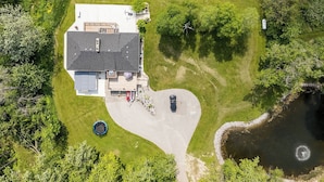 An aerial view of a house with a driveway, a swimming pool, and a small dock. - 5-Bedroom Countryside Estate in Northern GTA – Ideal for Gatherings & Getaways (Bolton)