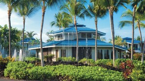 Un resort con un edificio de dos pisos, palmeras y un jardín bien cuidado.