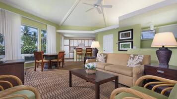 A living room with a sofa, two armchairs, a coffee table, and a dining area with chairs and a table.