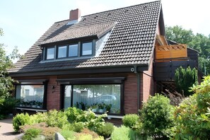 A modern house with a sloped roof, large windows, and a garden.