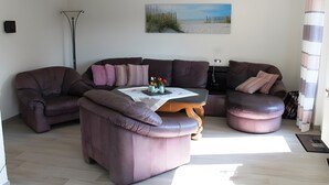 A modern living room with a sectional sofa, a coffee table, and a painting of a beach scene.