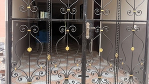 A black metal gate with decorative swirls and yellow accents.