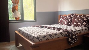 A bedroom with a bed, curtains, a window, and a view of greenery outside.