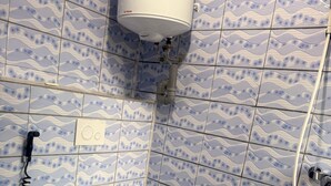 A bathroom with a toilet, a wall-mounted water heater, and a shower.