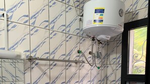 Ein Badezimmer mit Toilette, Waschbecken und einem an der Wand montierten Warmwasserbereiter.