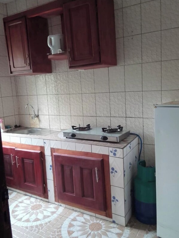 A kitchen with a gas stove, a sink, and wooden cabinets.