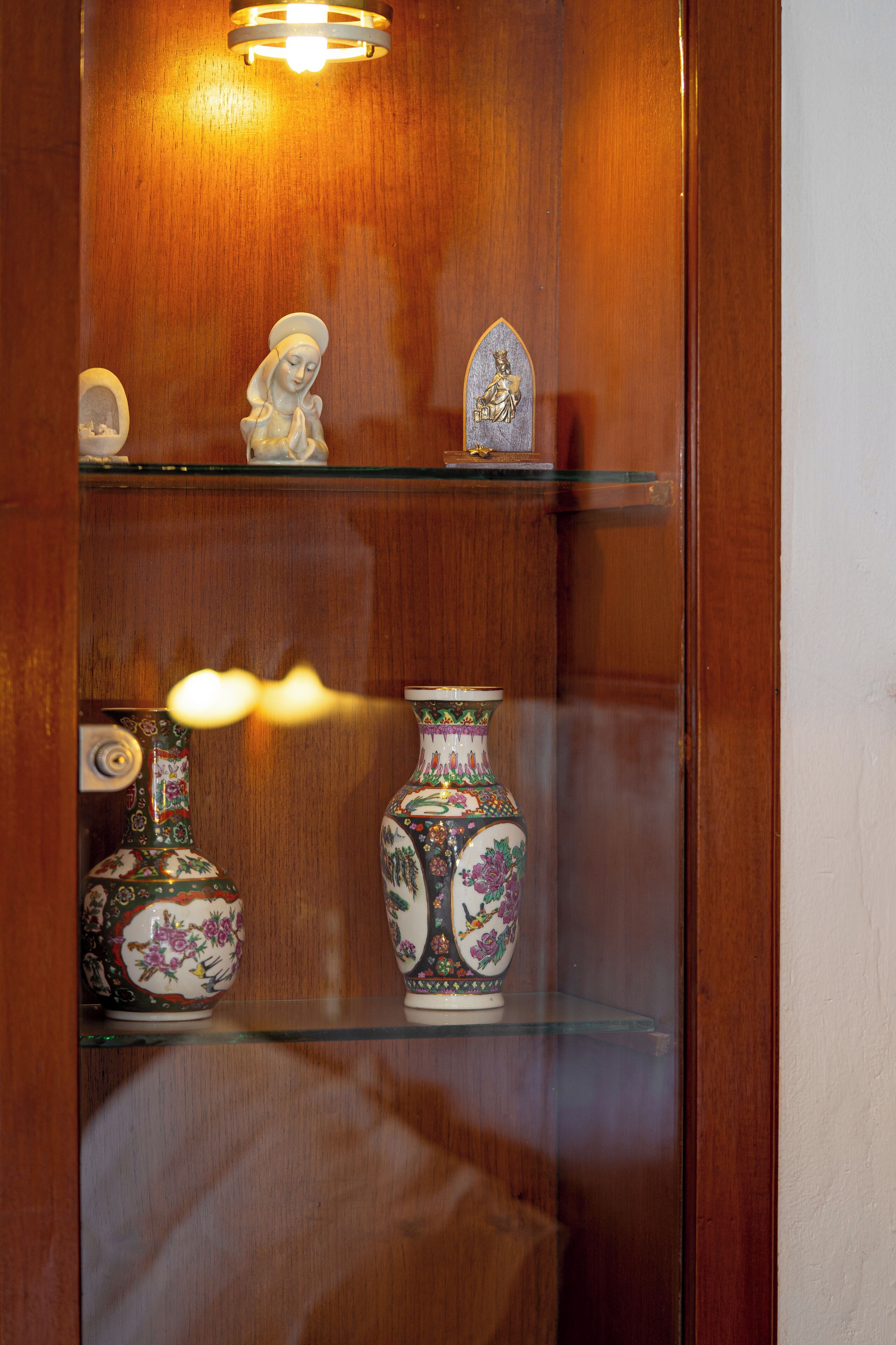 Een houten kast met glazen planken waarop decoratieve objecten staan.