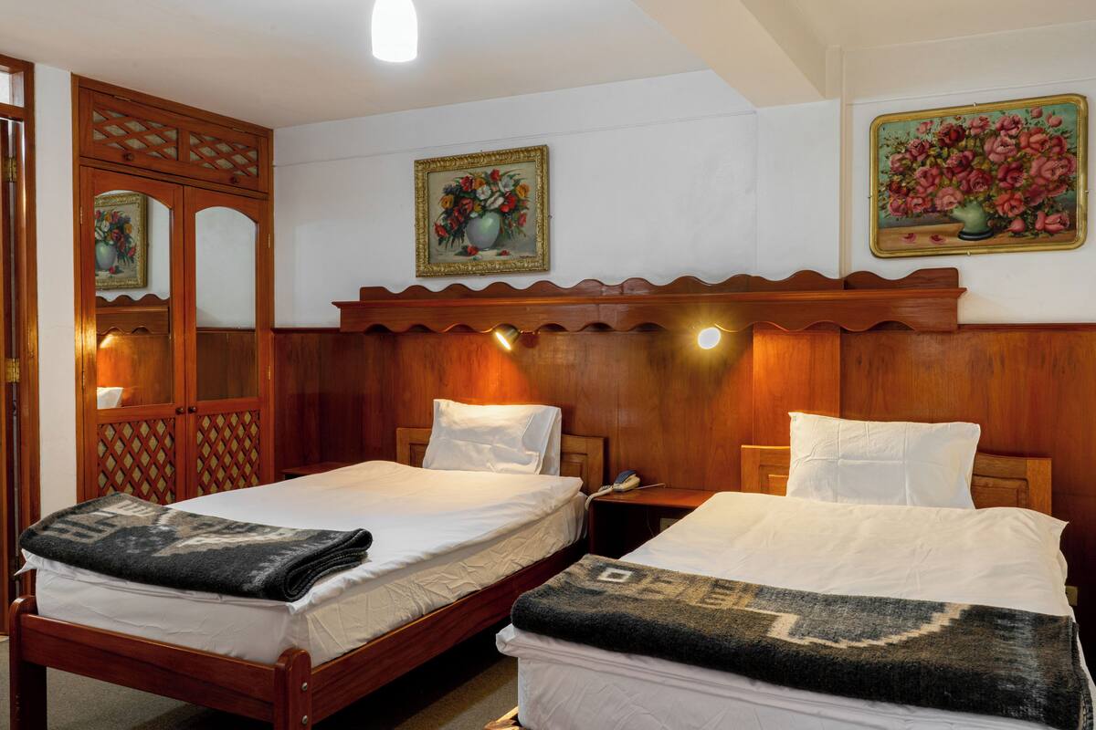 A hotel room with two beds, wooden headboards, and wall-mounted artwork.