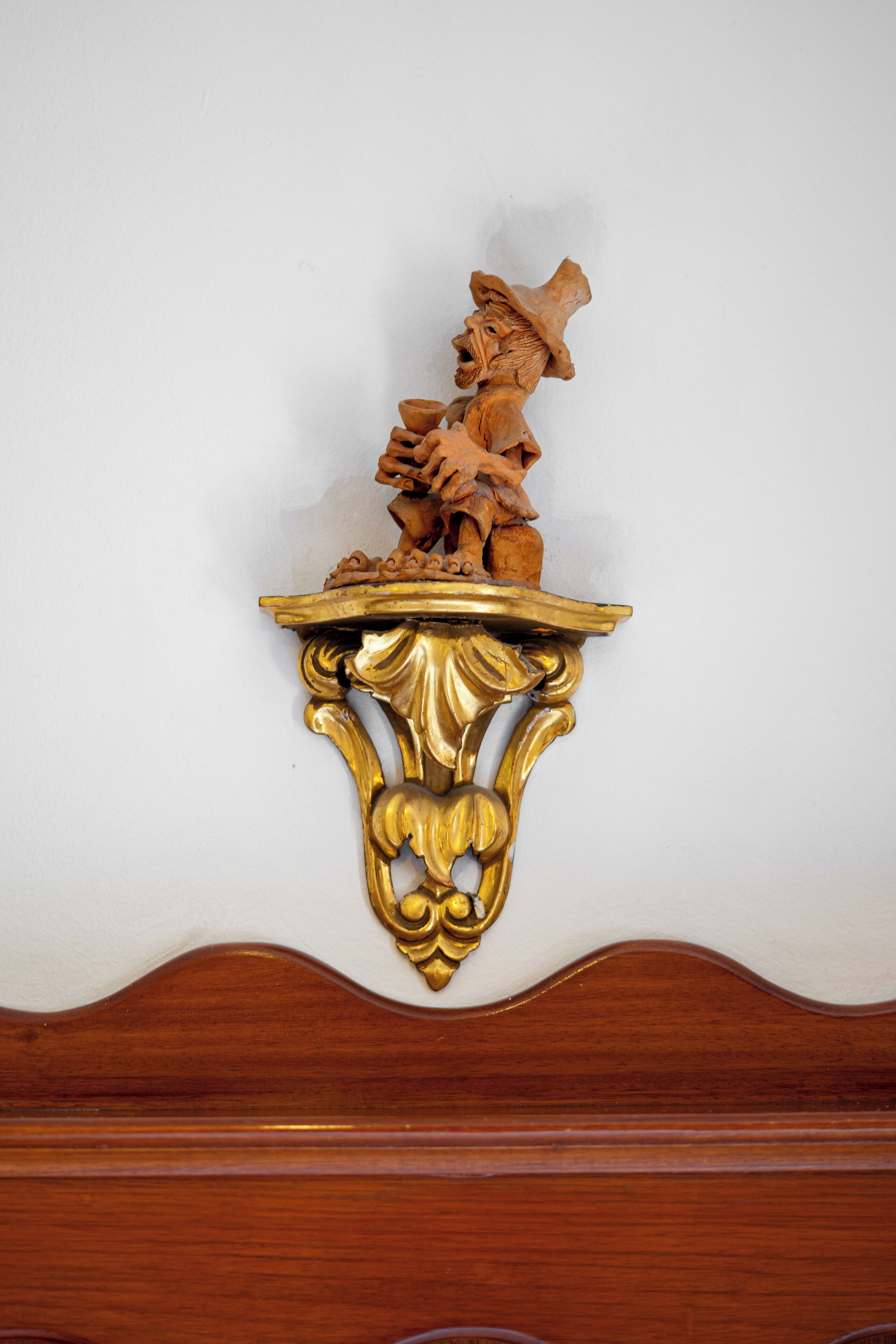Una pieza decorativa de pared con una figura y una base dorada.