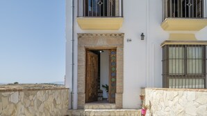 A two-story building with a stone facade, a wooden door, and a balcony with metal railings. - Apartment 'Las Niñas' with Private Terrace, Wi-Fi and Air Conditioning (Olvera)