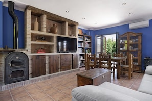 A living room with a fireplace, television, and a dining area with wooden furniture. - Apartment 'Las Niñas' with Private Terrace, Wi-Fi and Air Conditioning (Olvera)